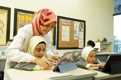 QIIS teacher guiding students with digital learning tools